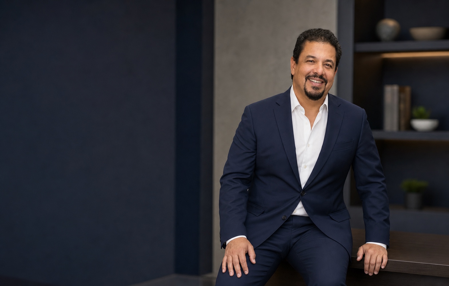 Editorial portrait of Dr. Hector Roldan in a navy suit